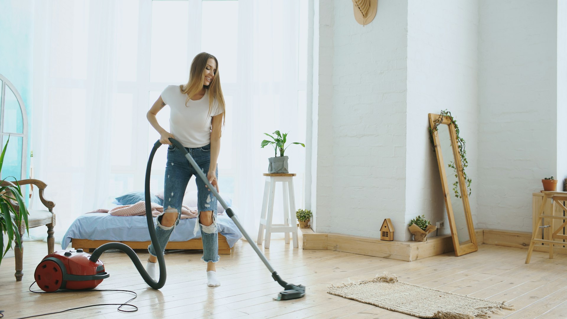 A person wearing gray work attire is using a pressure washer to clean a stone surface in a garden area surrounded by neatly trimmed hedges.